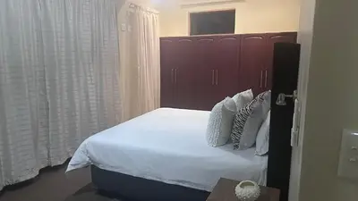 a bedroom with a bed with white sheets and pillows at GBL Reine Chateau in Polokwane