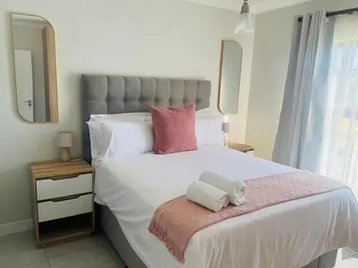 a bedroom with a large white bed with pink pillows at The Blyde Pretoria in Pretoria