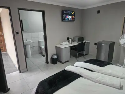 a bathroom with a bed and a sink and a mirror at Vation Nation Guest House in Mokopane