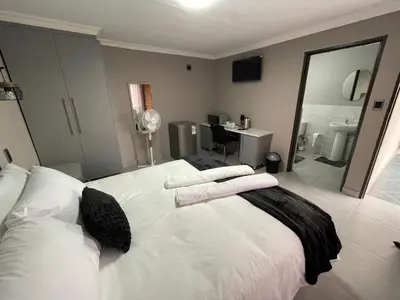 a bedroom with a white bed with towels on it at Vation Nation Guest House in Mokopane