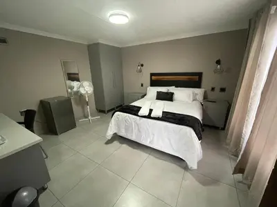 a bedroom with a large bed with white sheets and pillows at Vation Nation Guest House in Mokopane