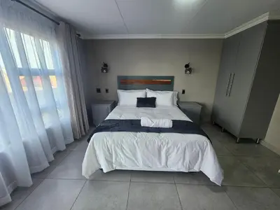 a bedroom with a large bed with white sheets and pillows at Vation Nation Guest House in Mokopane