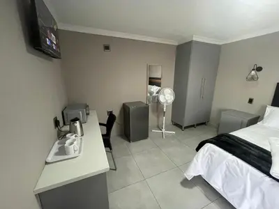 a bedroom with a bed and a desk and a sink at Vation Nation Guest House in Mokopane