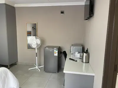 a room with a refrigerator and a fan at Vation Nation Guest House in Mokopane