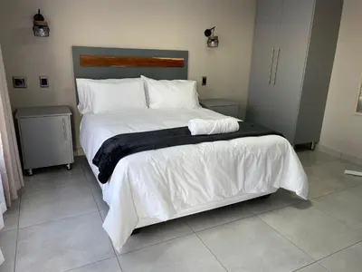 a bedroom with a large bed with white sheets at Vation Nation Guest House in Mokopane