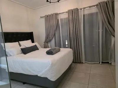 a bedroom with a large bed with white sheets and pillows at Aurora Executive Stay In Waterfall City in Midrand