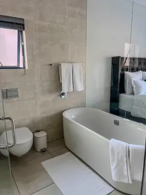 a white bathroom with a tub and a toilet at Aurora Executive Stay In Waterfall City in Midrand