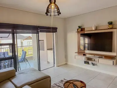 a living room with a couch and a tv at Aurora Executive Stay In Waterfall City in Midrand