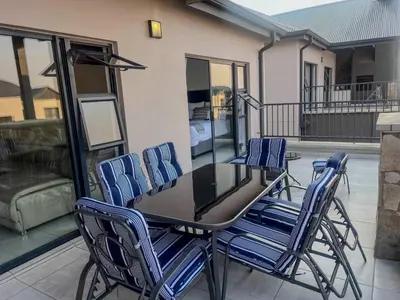 a table and chairs on a patio with a balcony at Aurora Executive Stay In Waterfall City in Midrand