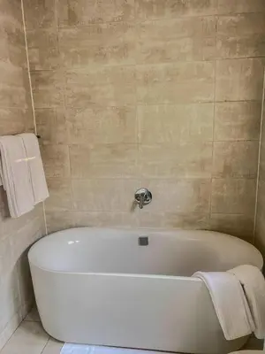 a white bath tub in a bathroom with towels at Aurora Executive Stay In Waterfall City in Midrand
