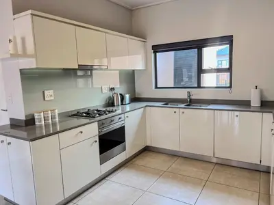a kitchen with white cabinets and a stove top oven at Aurora Executive Stay In Waterfall City in Midrand