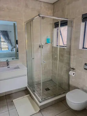 a bathroom with a shower with a toilet and a sink at Aurora Executive Stay In Waterfall City in Midrand