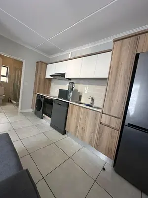 a kitchen with wooden cabinets and a black refrigerator at The Blyde Crystal Logon in Pretoria