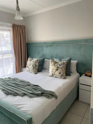 a bedroom with a bed with a blue headboard and pillows at The Blyde Crystal Logon in Pretoria