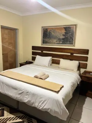 a bedroom with a large white bed with two towels on it at Khanxana guesthouse in Olifantsfontein
