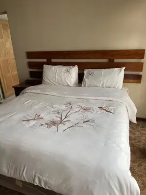 a white bed with white pillows and trees on it at Khanxana guesthouse in Olifantsfontein