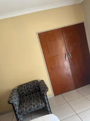 a room with a couch and a wooden door at Khanxana guesthouse in Olifantsfontein