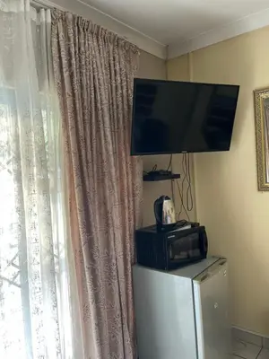 a flat screen tv sitting on top of a refrigerator at Khanxana guesthouse in Olifantsfontein