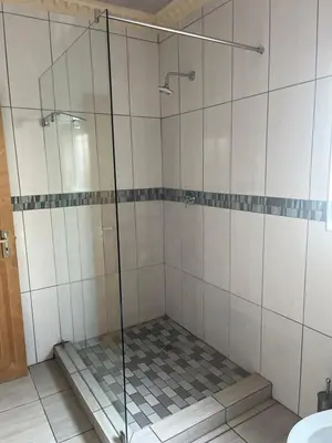 a shower with a glass door in a bathroom at Khanxana guesthouse in Olifantsfontein
