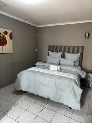 a bedroom with a large bed with a blue comforter at Tranquil Leisure in Midrand