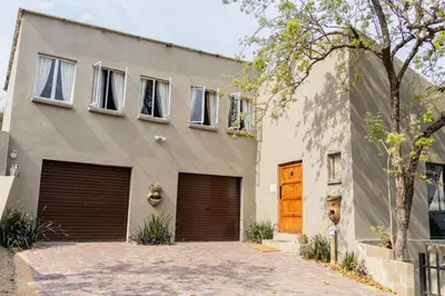 a gray building with two garage doors and a tree at Ses'fikile