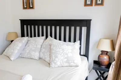 a bed with white sheets and pillows and two lamps at Ses'fikile