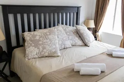 a bed with white pillows and a black headboard at Ses'fikile