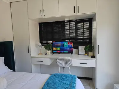a bedroom with a bed and a desk with a television at The Little Haven in Midrand