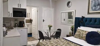 a bedroom with a bed and a table and a kitchen at The Little Haven in Midrand
