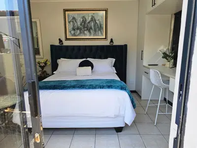 a bedroom with a large bed and a desk at The Little Haven in Midrand