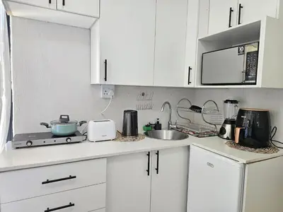 a white kitchen with white cabinets and a sink at The Little Haven in Midrand