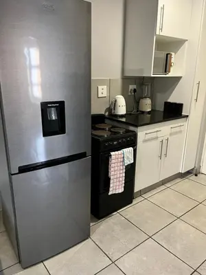 a kitchen with a black refrigerator and white cabinets at Wotela in Chartwell