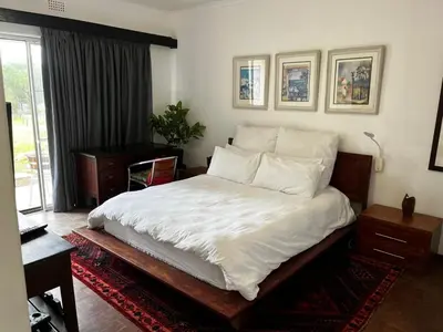 a bedroom with a large bed with white sheets and pillows at Cactus Road Guest House in Midrand