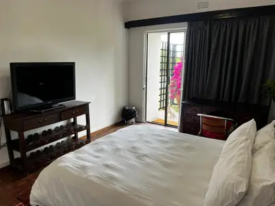 a bedroom with a bed and a flat screen tv at Cactus Road Guest House in Midrand