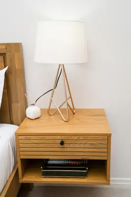 a wooden nightstand with a lamp on it next to a bed at Real Kee in Midrand
