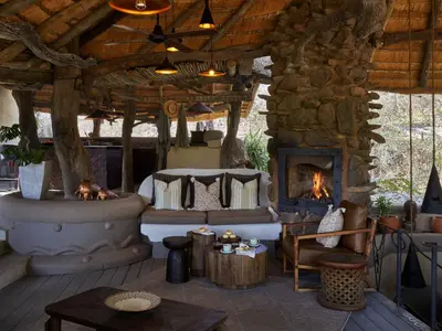 an outdoor living room with a stone fireplace at Toro River by Newmark in Makalali Game Reserve