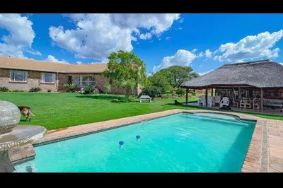 a large swimming pool in a yard with a house at Elysium Falls House in Roodeplaat