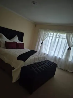 a bedroom with a large bed and a window at Elysium Falls House in Roodeplaat