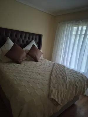 a bedroom with a bed with pillows and a window at Elysium Falls House in Roodeplaat