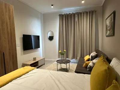 a bedroom with a bed and a couch and a tv at Delarose business leisure Studio in Pretoria