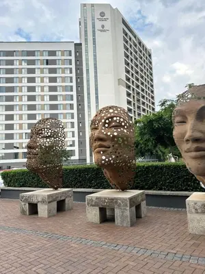 twoulptures of heads sitting on benches in front of a building at Delarose business leisure Studio in Pretoria