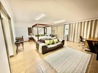 a living room with a couch and a bed at Austin Manor in Midrand