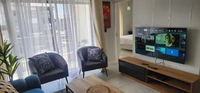 a living room with a flat screen tv and two chairs at The Blyde Crystal Lagoon in Pretoria