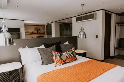 a bedroom with a bed with an orange blanket and pillows at The Villa Palms in Pretoria