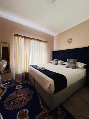 a bedroom with a large bed with a blue headboard at Royal Apartments in Burgersfort