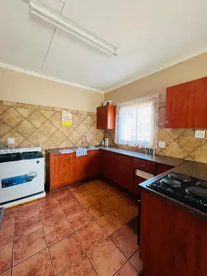 an empty kitchen with wooden cabinets and a stove at Royal Apartments in Burgersfort