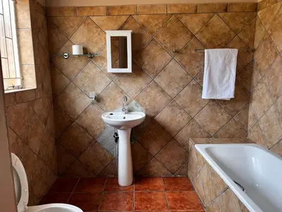 a bathroom with a sink and a toilet and a tub at Royal Apartments in Burgersfort