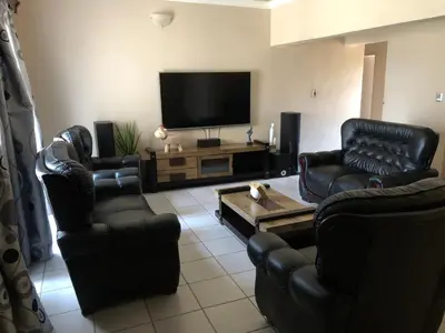a living room with leather chairs and a flat screen tv at Horizon small holding in Polokwane