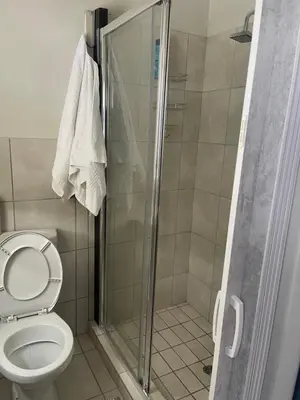 a bathroom with a toilet and a glass shower at Lani Accommodation in Pretoria