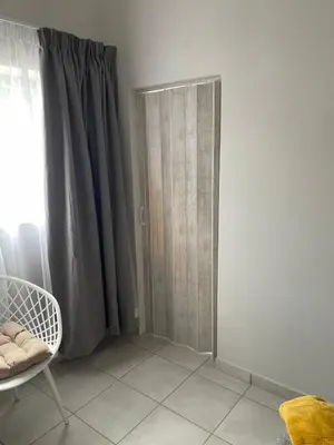 a room with a curtain and a chair and a window at Lani Accommodation in Pretoria